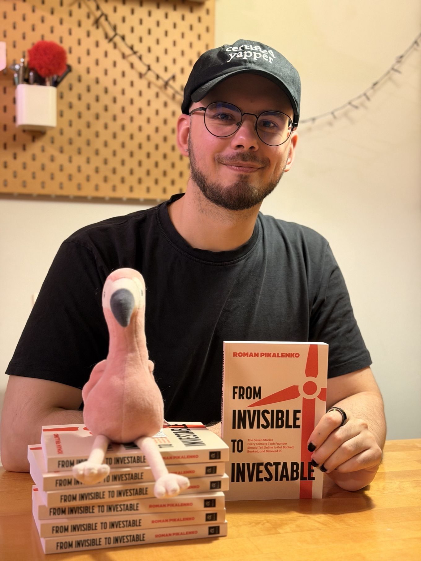 Roman Pikalenko holding a copy of From Invisible to Investable, next to a stack of copies