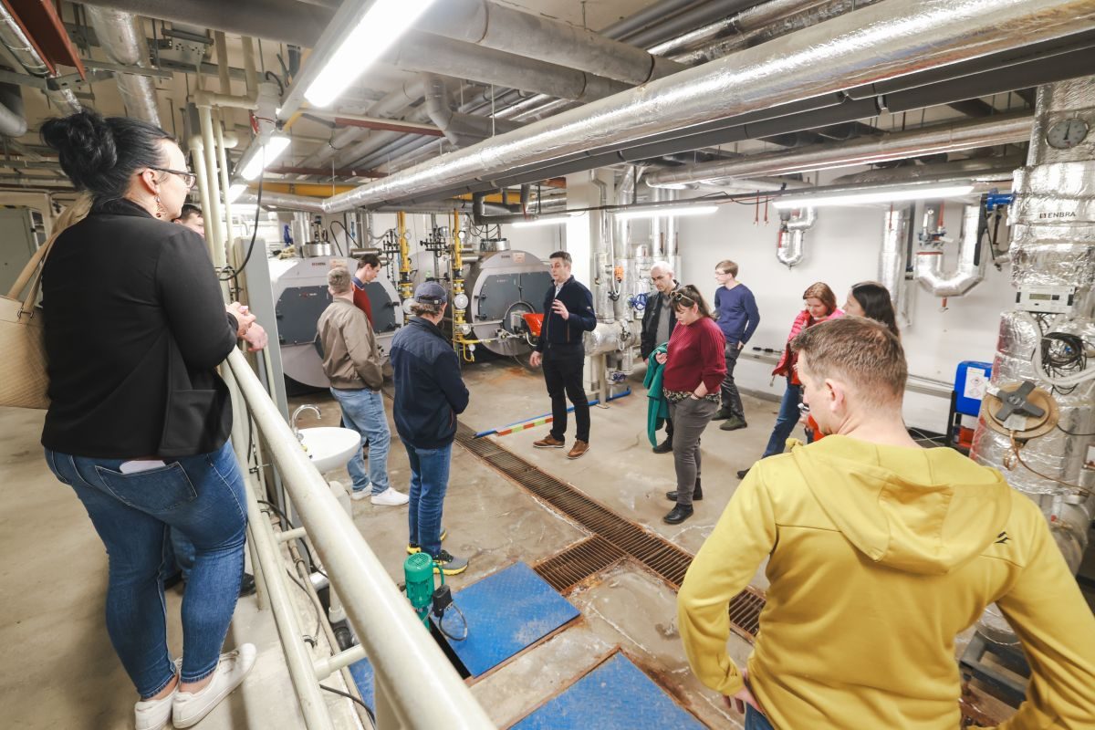 A group touring a plant room of boilers and pipework at Břeclav hospital.
